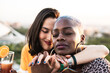 © ADDICTIVE STOCK - Multiracial lesbian couple sitting close together outdoors