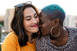 © ADDICTIVE STOCK - Multiracial lesbian couple sitting close together outdoors