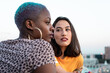 © ADDICTIVE STOCK - Multiracial lesbian couple sitting close together outdoors