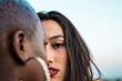 © ADDICTIVE STOCK - Multiracial lesbian couple sitting close together outdoors