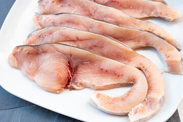 Close-up of various slices of raw swordfish, in a white plate, on a slate table..Tasty food from Italian cuisine and from the Mediterranean sea. Concept for a tasty and healthy meal.