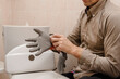 Close up photo of a professional handyman putting on protective gloves to repair a toilet cistern