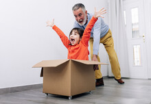 Child Playing In Racer In Carton Box With Grandfather