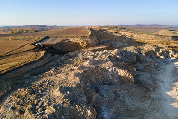 Wall Mural - Aerial view of open pit mine of sandstone materials for construction industry with excavators and dump trucks. Heavy equipment in mining and production of useful minerals concept