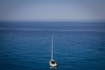 Sticker - Drone view of a boat in a sea with trees and mountains in the background