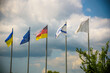 The flag of the European Union and flags of Ukraine, Israel, Germany flutter in the wind in different directions against the blue sky. Bottom side view