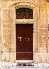 Wall Mural - Vertical shot of a vintage brown front door of a yellow brick building in Valetta, Malta