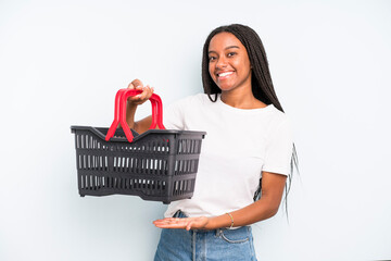 Wall Mural - black pretty woman smiling cheerfully, feeling happy and showing a concept. empty shopping basket