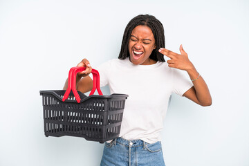 Wall Mural - black pretty woman looking unhappy and stressed, suicide gesture making gun sign. empty shopping basket