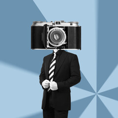 a young businessman in a black business suit headed by huge old vintage retro photo camera standing 