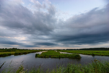Wall Mural - scenic view of threatening clouds over the watery dutch landscape near gouda, holland