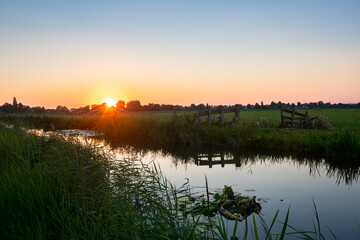 Wall Mural - The sun goes down over the watery Dutch landscape in the western part of the country.