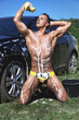 © IgorKireev - Muscular sexy wet young handsome guy with athletic body in yellow swimming trunks washes the car with soap and foam. Fitness male model smeared the body with foam