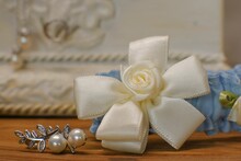 Silver Brooch With Pearls And Rose Wedding Garter On Wooden Table