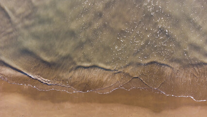 Top view of texture waves sandy beach.