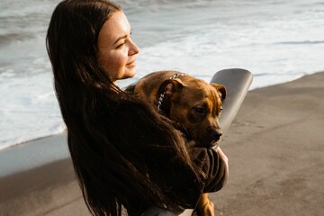 Wall Mural - Beautiful caucasian woman carries American bully puppy. Ocean background