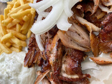 Closeup Of Isolated Ready To Eat Greek Pork Gyros Plate With Onions, French Fries And Tzatziki Dip
