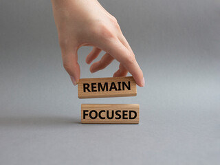 Remain focused symbol. Concept words Remain focused on wooden blocks. Beautiful grey background. Businessman hand. Business and Remain focused concept. Copy space.