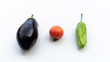 group of an organic eggplant, tomato and pepper from the garden on a white surface