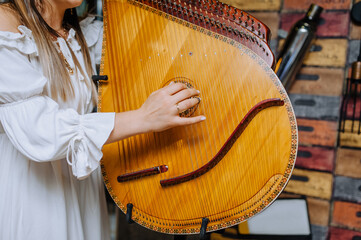 A girl musician in an embroidered shirt plays the bandura, a musical Ukrainian national traditional instrument.