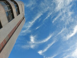 Sticker - Low-angle shot of a tall modern building against a blue cloudy sky