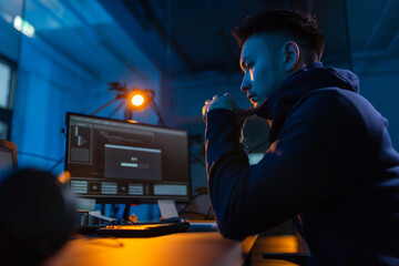 Poster - cybercrime, hacking and technology concept - male hacker in dark room using computer virus program for cyber attack