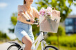 © Syda Productions - people, leisure and lifestyle - close up of woman with flowers and bag in basket of bicycle on city street