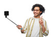 people concept - happy smiling young man in glasses taking picture with smartphone on selfie stick over white background