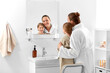 © Syda Productions - beauty, hygiene, morning and people concept - happy smiling mother and daughter looking to mirror in bathroom
