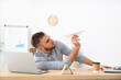 Lazy office employee playing with paper plane at workplace