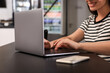 © New Africa - Happy young woman using laptop at table in hostel dining room, closeup