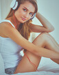 © lenets_tan - Portrait of beautiful woman in morning listening music sitting on bed at home