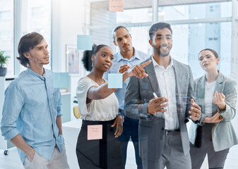 Teamwork, collaboration and planning with a team and their manager working on the vision, mission and strategy for their business. Writing on a glass wall with sticky notes for growth and development