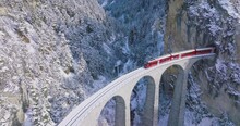 Landwasser Viaduct World Heritage Sight With Luxury Glacier And Bernina Express In Swiss Alps Snow Winter Scenery. Aerial Drone Shot Red Train Passing Through Famous Mountain In Filisur, Switzerland.