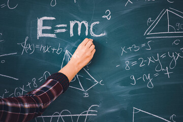 Teacher or student writing on blackboard during math lesson in school classroom
