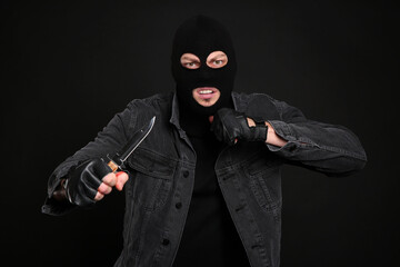 Wall Mural - Man in mask with knife on black background. Dangerous criminal