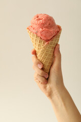 Wall Mural - Woman holding waffle cone with delicious pink ice cream on white background, closeup