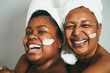 African mother and daughter doing beauty treatment at home using skin mask - Focus on girl face