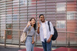 © Look! - Positive young caucasian interracial young guy with girl waving hands standing on street. Students wearing casual clothes take break outside college.