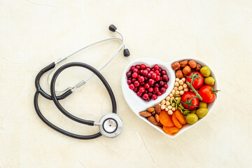 Wall Mural - Cholesterol diet concept. Healthy food in heart shaped dish with stethoscope