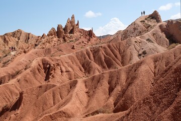 Silhouettes of two persons on top in Fairytale Canyon or Skazka Canyon, a colourful natural attraction on the southern shore of Lake Issyk Kul, Kyrgyzstan, Central Asia