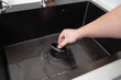 A man's hand holds a plug for a drain hole to fill water. modern kitchen sink. Copy space for text