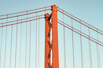 Iconic orange red suspension bridge over Tagus River in Lisbon, Portugal. 25 de Abril Bridge, 25th of April Bridge at golden hour sunset.