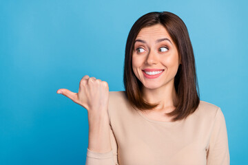 Wall Mural - portrait of cheerful nice lady look direct thumb finger empty space isolated on blue color backgroun