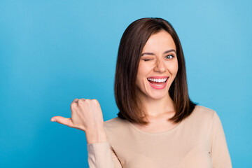 photo of positive funky girl eye wink indicate thumb finger empty space isolated on blue color backg