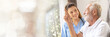 © SKW - Web banner Man being cared for by a private Asian nurse at home suffering from Alzheimer's disease to closely care for elderly patients with copy space on left