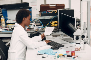 Scientist african american woman working in laboratory with computer and typing scientific text. Research and development of electronic devices by color black woman.