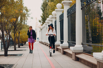 Wall Mural - Young woman with electric scooter at the city.