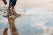 Leinwandbild Motiv Woman wearing rain rubber boots walking running and jumping into puddle with water splash and drops in autumn rain.
