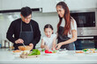© nikomsolftwaer - Asian family cooking at home. Happy family cooks together in the kitchen home recreation and weekend meal prep.